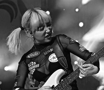 Blonde haired girl in black top playing a Fender Stratocaster electric guitar on stage
