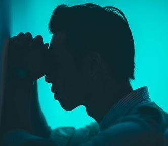 The image of a sad man with hands pressed on eyes