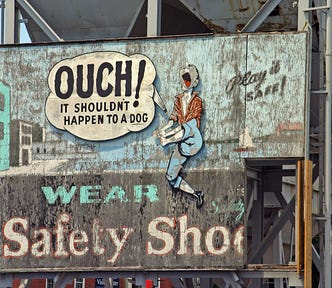 Cartoon person shouting “Ouch! It shouldn’t happen to a dog.” Below in text is “Wear safety shoe.”