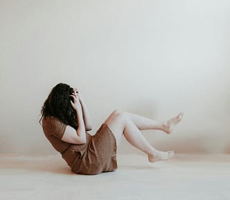 woman in anguish sitting on the ground covering her face with her hair and hands, grief, loss,