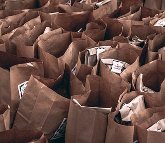 A photo of many brown grocery sacks filled with donated foods