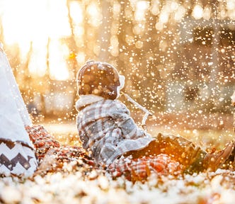A toddler outside a tent wearing a winter jacket