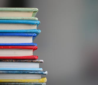 A stack of books — colored green, aquamarine, blue, red, grey and yellow.