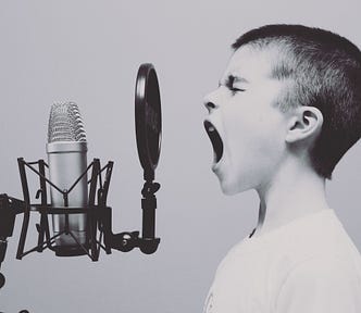 A kid yelling into a microphone. To Kill a Mockingbird by Harper Lee.