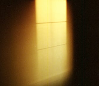 A window’s light projected in the dark against a wall