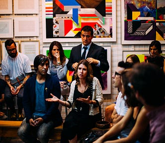 A woman speaking in the middle of a group in a room