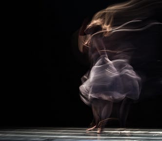 Long exposure photograph with a dancer in motion on a black background