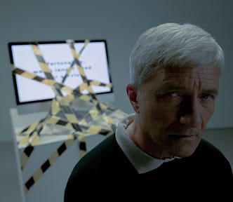 An elderly man sitting and typing on computer with information that he is dismissed