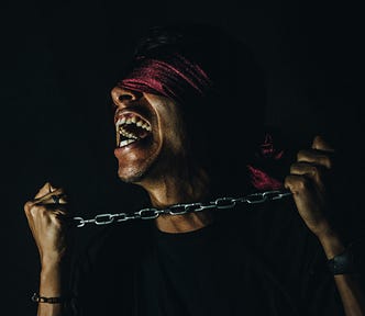 A blindfolded man trying hard to break free from a chain