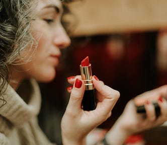 A lady trying on red lipstick.