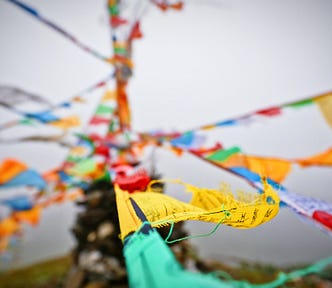 A variegated arrangement of colourful prayer flags with written words in Nepal flying through the winds on top of a misty mountain