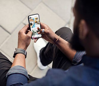 Photo looking over the shoulder of a man using Pinterest on his mobile device.