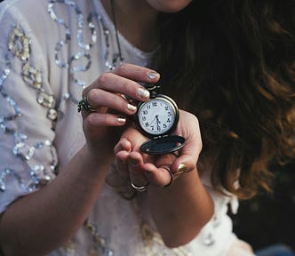 A woman holds up a clock to show the time