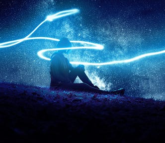Person sitting on a hillside with a stream of light around them.