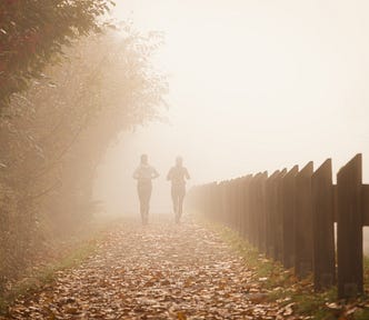 two women jogging down a misty path