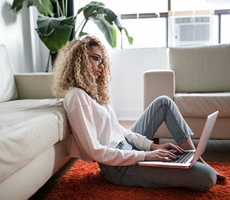 Woman with curly hair working at a laptop. Hybrid Work. Remote Work. Productivity
