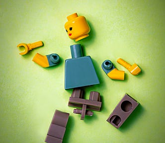 A female lego person is broken into pieces.