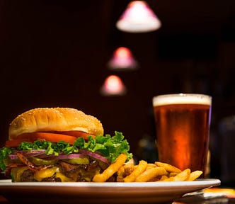 A plate with a burger and fries and a pint of beer.