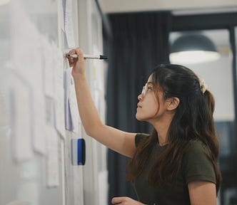 woman writes on whiteboard with a dry erase marker