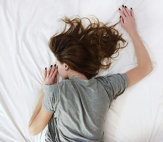 a dark-haired woman lying facedown on a bed