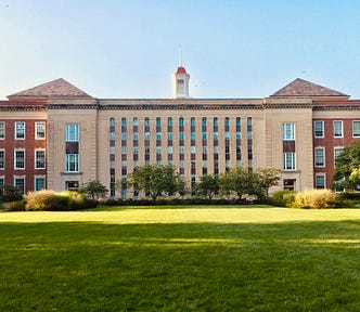 picture of a university building with a vast green lawn out front. graduate school. university. going back to school.