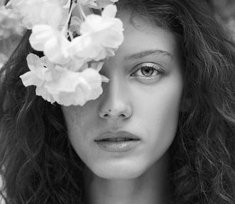 Sad woman with white flowers covering one eye