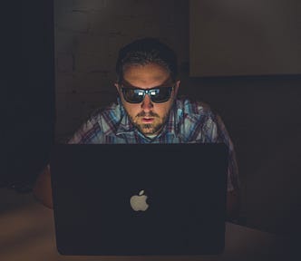 open-mouthed white guy with sunglasses staring at a mac laptop