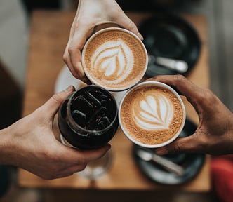 three hands holding three coffee cups