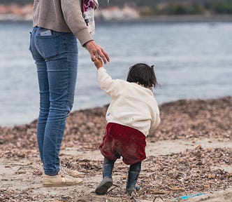 A woman holding a toddler walking