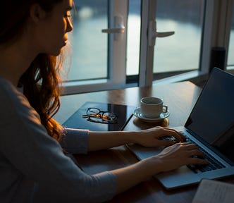 Woman sitting at a laptop typing.
