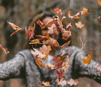 A woman lets go of leaves in nature