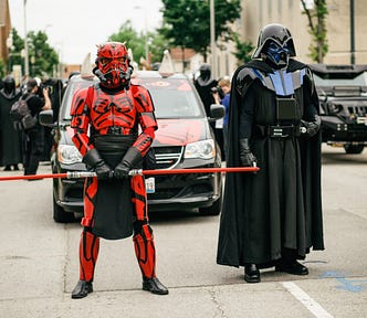 Two Star Wars cosplayers, one dressed as Darth Maul, the other dressed as Darth Vader.