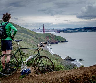 A cyclist stops to admire a cliffside view of the sea