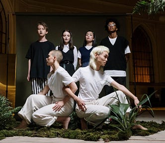 Conceptual photo of dancers clothed in white with people clothed in black behind them.