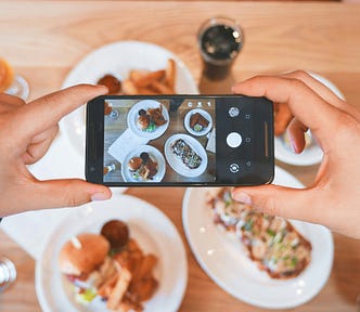 A smartphone being held over a meal at a restaurant to take a picture