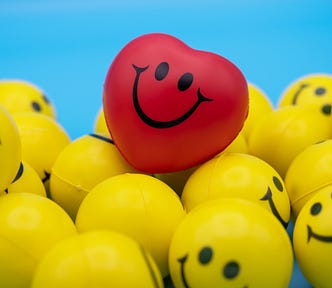 red hear with smiley face atop yellow balls with smiley faces