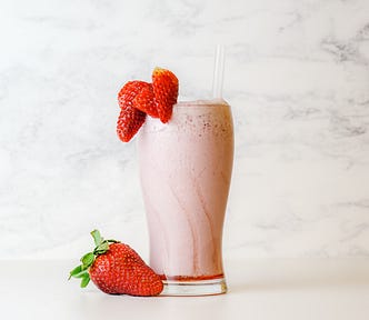 A tall glass of strawberry milkshake.