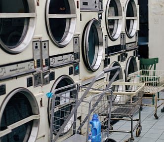 An old coin laundromat with three wire laundry carts