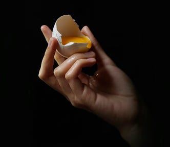 Image of hand holding a broken egg.