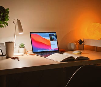 A writer’s Macbook on a dimly lit wooden desk.