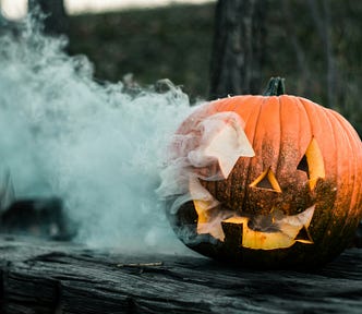 Pumpkin burning from the inside and a haunted house in the background