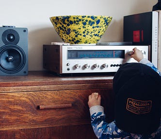 A kid adjusting the volume on a stereo.