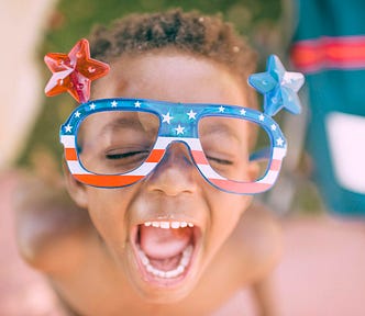 A child in patrotic glasses screaming with their mouth open