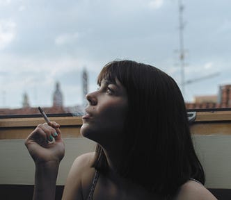 Non-ejaculation practice. A womanblowing out smoke from inhaling a smoke.