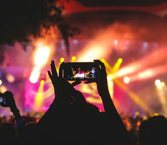 A person holding up a phone to record a concert