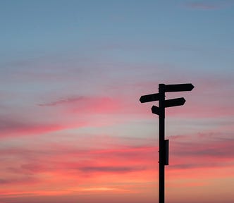 A signpost against a sunset sky