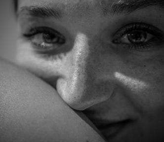 Black and white image of women half smiling at camera.