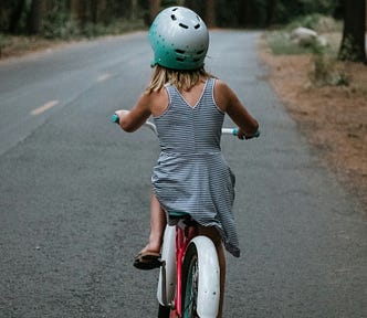 Young girl riding a bike down the road photo taken from the back