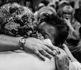 two middle age people hugging in a crowded room