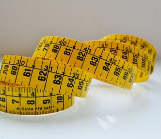 Yellow measuring tape on neutral background